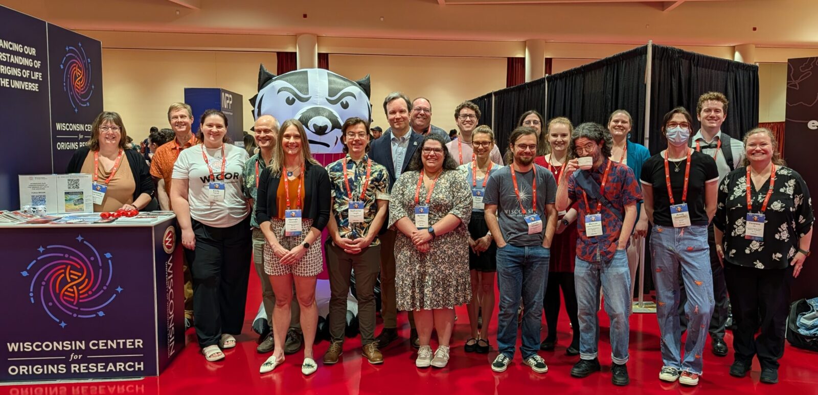 Group photo of WiCOR members attending AbSciCon2026 with the WiCOR Booth in the left of the photo and an inflatable Bucky Badger behind them