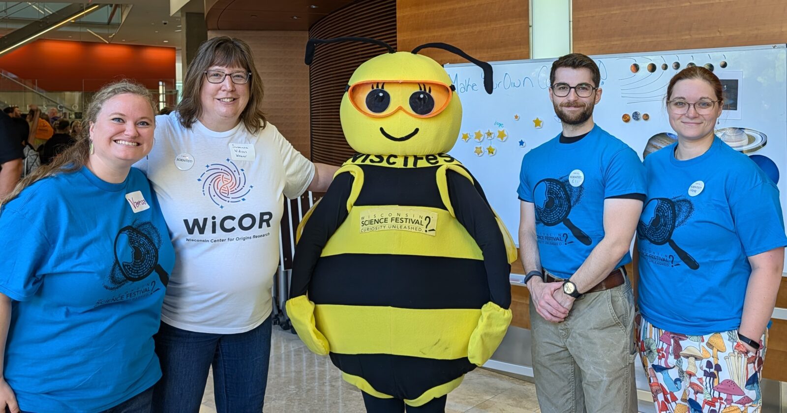 WiCOR WiSciFest presenters pose for a photo with mascot Beesly. The WiCOR Logo is at the top on a dark blue background and the bottom says WiSciFest 2026.